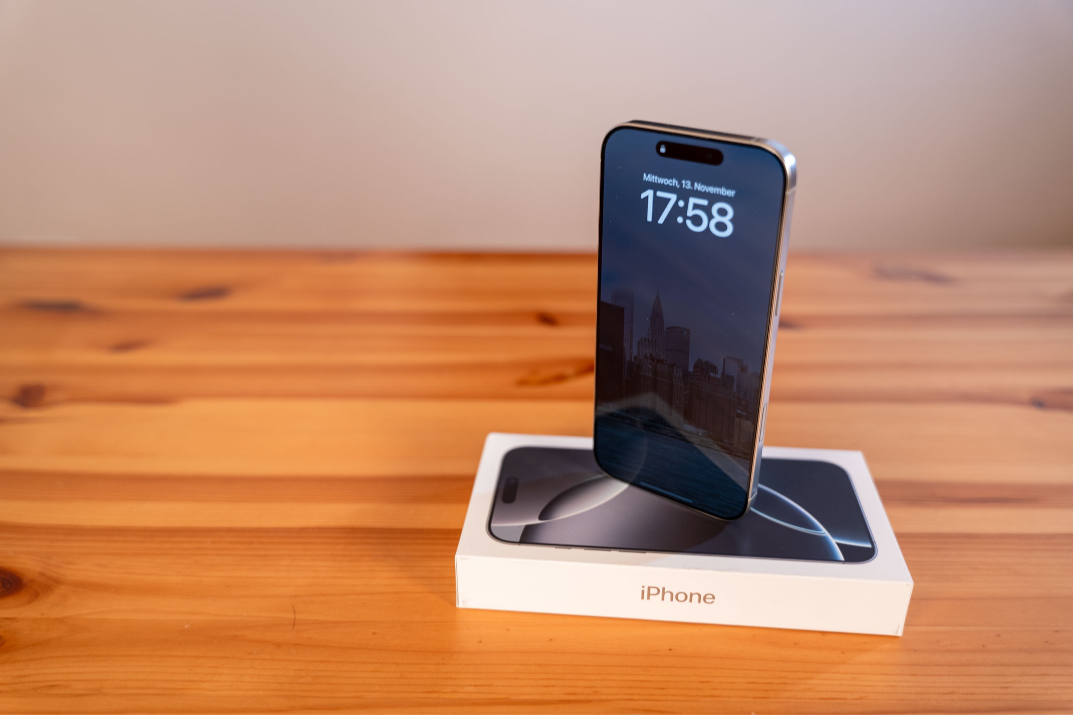 Ein neues Smartphone steht auf einer Verpackung auf einem Holztisch.