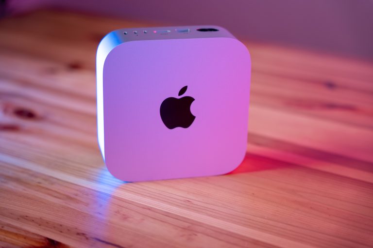 Apple Mac Mini auf einem Holztisch mit bunter Beleuchtung.