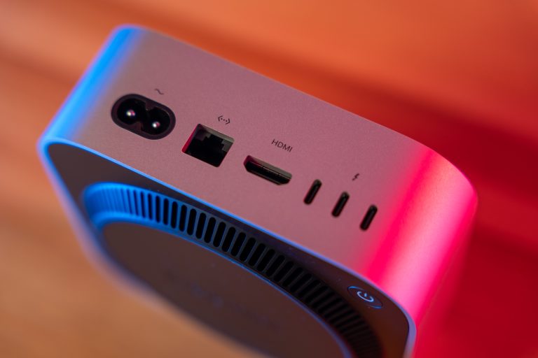 Nahaufnahme der Anschlüsse auf der Rückseite eines technischen Geräts. Sichtbar sind ein Stromanschluss, Ethernet-Port, HDMI-Anschluss und drei USB-C-Anschlüsse. Das Gerät hat ein modernes Design mit blauer und roter Beleuchtung.